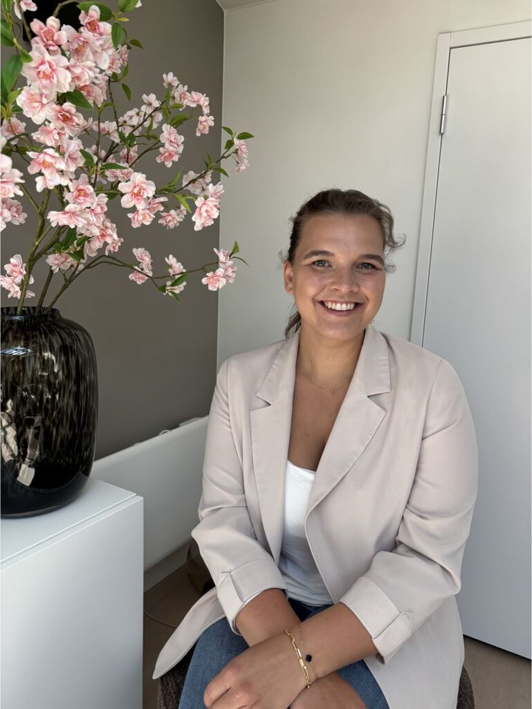 Judith smits osteopaat lachend op stoel in haar kliniek